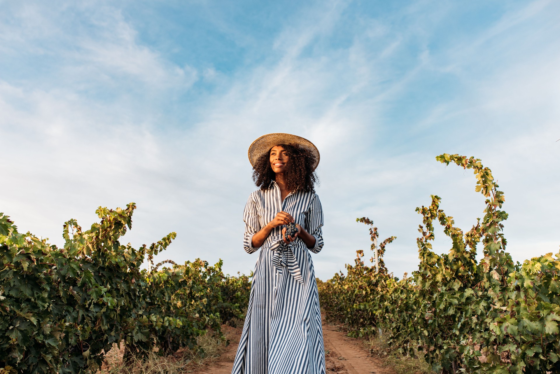 Young woman walking in a path in the middle of a vineyard